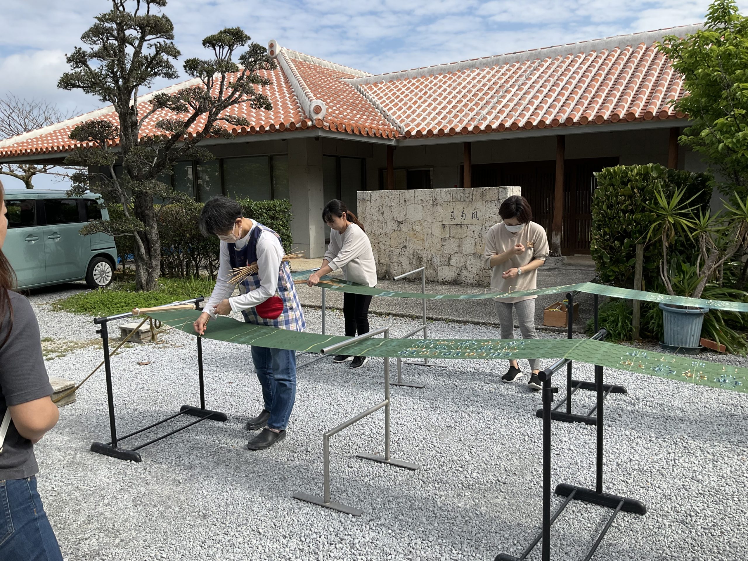 織り上がった帯を伸子針でピンと張って水で洗う織り子のみなさん。